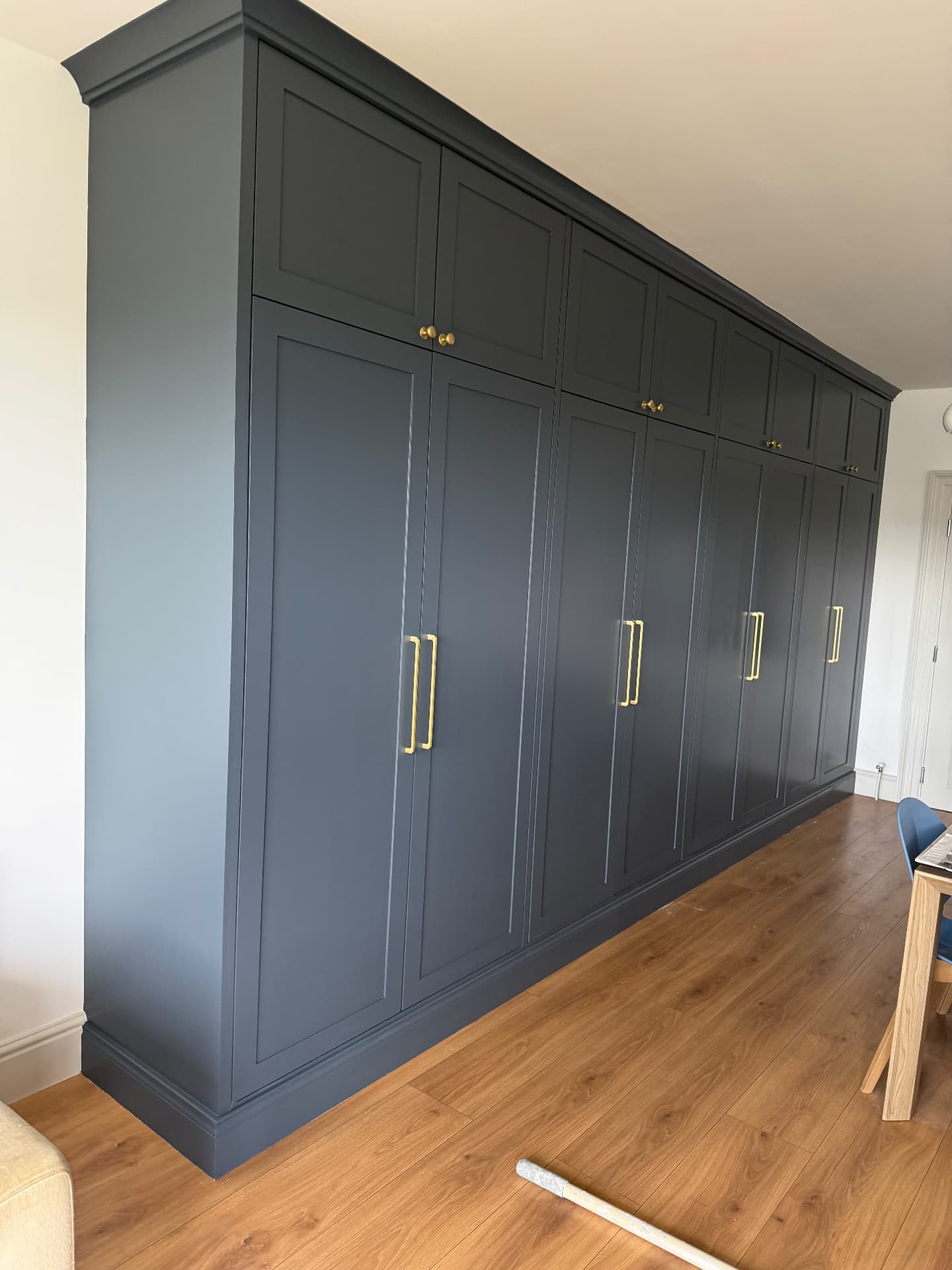 Fitted wardrobe doors and cornicing spray-painted in dark grey with brass handles